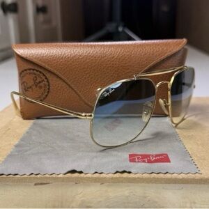 Ray-Ban sunglasses with a gold metal frame and blue gradient glass lenses.